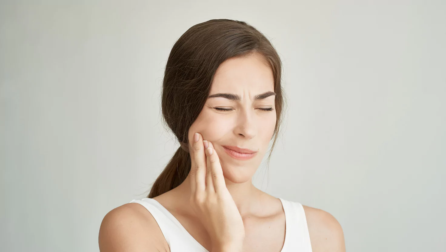 A worried patient holding their jaw in pain (before treatment).